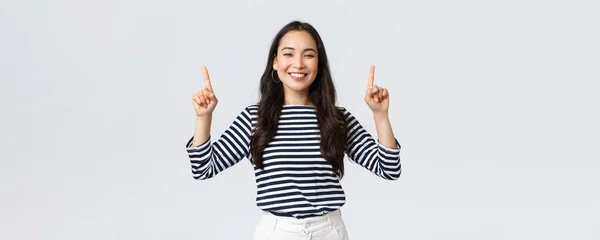 Lifestyle, beauty and fashion, people emotions concept. Cheerful good-looking female model pointing fingers up to shop promotion banner, smiling camera, recommend click link to online store — Stock Photo, Image
