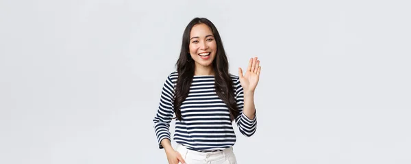 Estilo de vida, emoções das pessoas e conceito casual. amigável alegre asiático mulher sorrindo, dizendo oi e acenando mão para cumprimentar pessoa, fazer Olá gesto, bem-vindo alguém — Fotografia de Stock