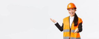 Gülümseyen başarılı Asyalı kadın inşaat yöneticisi, mimar projesini tanıtır, projeyi planına işaret eder, bina planını açıklar. Endüstriyel kadın yatırımcılara konuşma yapıyor