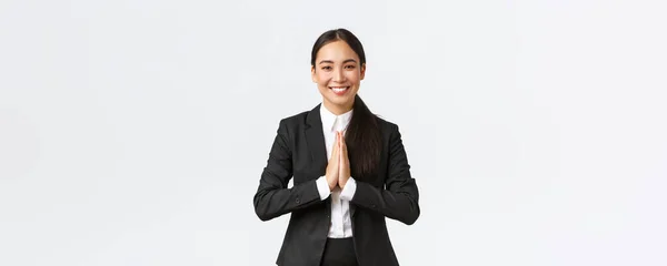 Remélhetőleg boldog ázsiai üzletasszony fekete öltönyben udvariasan meghajol és azt mondja namaste, üdvözlő ügyfelek és mosolygós barátságos. Hálás női menedzser megköszöni a segítséget, hogy hálás, értékelik segítséget — Stock Fotó