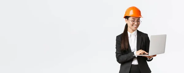 성공 한 아시아인 여성 기술자, 안전 헬멧의 공장 매니저, 노트북 컴퓨터를 사용하는 비즈니스 슈트, 프로젝트나 청사진을 컴퓨터로 검사하는 모습 — 스톡 사진