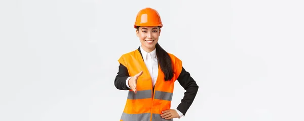 Σίγουρη επιτυχημένη γυναίκα αρχιτέκτονα, ηγέτης της κατασκευής στο κράνος ασφαλείας, ανακλαστικό σακάκι, extand χέρι για χειραψία, χαιρετισμό των επιχειρηματικών εταίρων στο χώρο του κτιρίου, στέκεται λευκό φόντο — Φωτογραφία Αρχείου