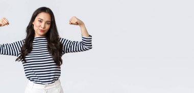 Yaşam tarzı, insanların duyguları ve gelişigüzel kavramlar. Güçlü ve kendinden emin Asyalı kadın kaslarını esnetiyor. Spor salonuna kaydolduktan sonra mükemmel vücuduyla övünüyor. Kaslarıyla, antrenmanlarıyla ve güçlü hissetmesiyle övünüyor.