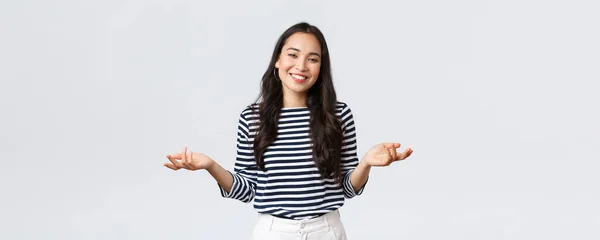 Lifestyle, beauty and fashion, people emotions concept. Smiling cute clueless girl dont have idea, no answer, shrugging with hands spread sideways, standing white background — Stock Photo, Image