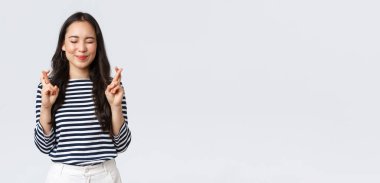 Yaşam tarzı, insanların duyguları ve gelişigüzel kavramlar. Umut dolu, sevimli Koreli kadın parmakları çapraz, gözleri kapalı ve gülümseyen, olumlu haberleri bekleyen, rüyalarının gerçekleşmesi için yalvaran