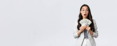 İş, finans ve istihdam, girişimci ve para kavramı. Şaşırmış ve nutku tutulmuş Asyalı genç iş kadını ev satarak ilk maaşını kazanıyor.