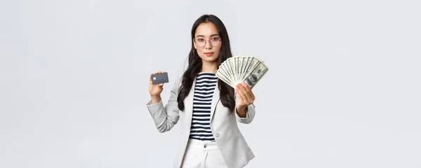 Бизнес, финансы и занятость, предприниматель и денежная концепция. Успешная азиатская предпринимательница показывает, как увеличиваются доходы, держат кредитные карты и деньги, улыбается камера — стоковое фото