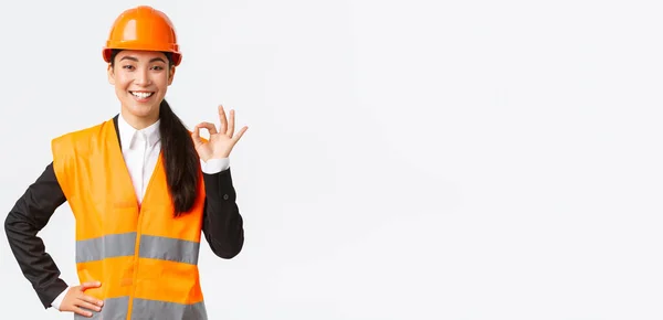 Architecte asiatique professionnelle confiante dans casque de sécurité assurer la qualité et le travail dans le temps, montrant un geste correct et souriant déterminé, debout affirmatif, assurer et garantir quelque chose — Photo