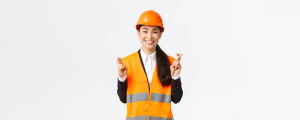 Reményteli és optimista mosolygós ázsiai női mérnök, építőipari vezető biztonsági sisak, amely hisz a projekt, keresztujjú sok szerencsét és pozitív, álló fehér háttér — Stock Fotó