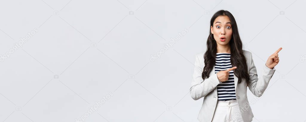 Business, finance and employment, female successful entrepreneurs concept. Intrigued businesswoman, asian real estate broker pointing fingers right and looking curious, find good deal