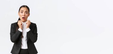 Endişeli ve şok olmuş takım elbiseli Asyalı bayan girişimci endişe verici haberleri duyuyor, el ele tutuşuyor ve endişeli bir şekilde soluk soluğa kalıyor, paniğe kapılıyor. İş kadınlarının sorunları var, korkunç sorunlar.