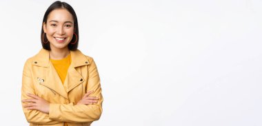 Sarı ceketli Asyalı kadın portresi, gülümsüyor ve mutlu görünüyor, beyaz arka planda duruyor.