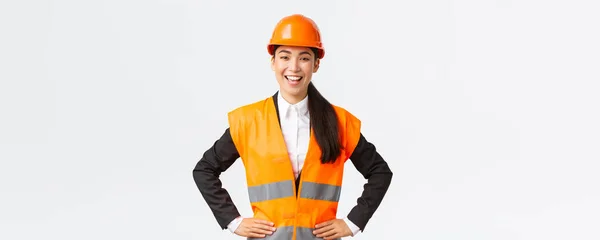 Succès jeune femme d'affaires asiatique, architecte en casque de sécurité, veste réfléchissante, debout confiant et déterminé, souriant assuré, la construction de maisons, posant sur fond blanc — Photo