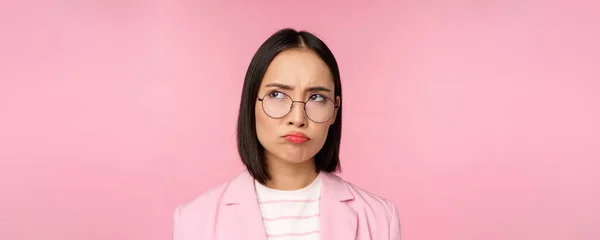 失望したアジアの実業家、オフィスの女性でガラス、見て動揺でスミス不公平な、説得力のある、ピンクの背景の上に立って — ストック写真