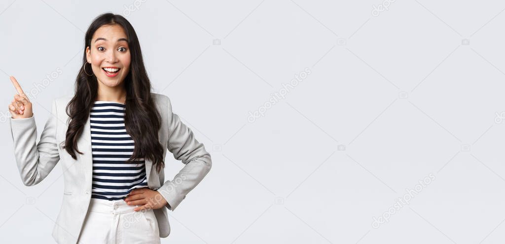 Business, finance and employment, female successful entrepreneurs concept. Cheerful successful businesswoman in white suit pointing fingers upper left corner, showing advertisement
