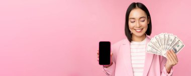 Koreli başarılı kurumsal kadın görüntüsü para, dolar ve akıllı telefon uygulaması ekranı, cep telefonu uygulaması arayüzü, yatırım ve finans kavramı, pembe arka plan