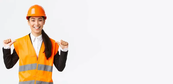 Exitosa orgullosa sonriente asiática gerente de construcción, ingeniera en casco de seguridad señalándose a sí misma, presumiendo. Arquitecto recomienda asistencia personal, alardear logros — Foto de Stock