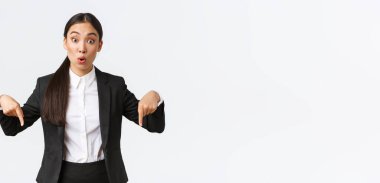 Heyecanlı ve etkilenmiş Asyalı kadın komisyoncu, büyük bir şey göstererek, parmaklarını aşağı işaret ediyor. Şaşkın iş kadını fiyat düşüşünü tartıştı, heyecan dolu bir ifadeyle en alttaki reklamı gösterdi