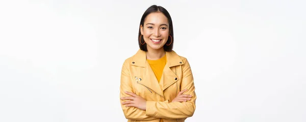 Portret van Aziatische vrouw in geel jasje, lachend en er gelukkig uitziend, staande over witte achtergrond — Stockfoto
