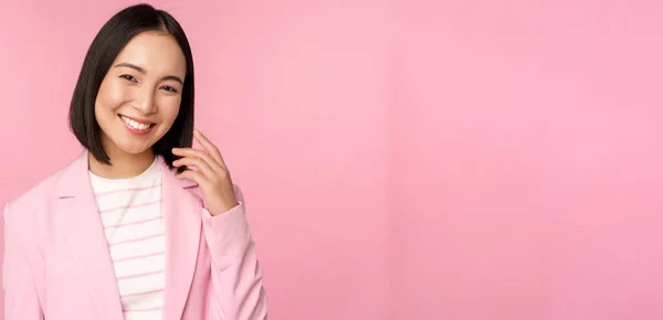 Νέοι επαγγελματίες. Χαμογελαστή Ασιάτισσα επιχειρηματίας, πωλήτρια με κοστούμι που δείχνει σίγουρη στην κάμερα, ποζάρει σε ροζ φόντο — Φωτογραφία Αρχείου