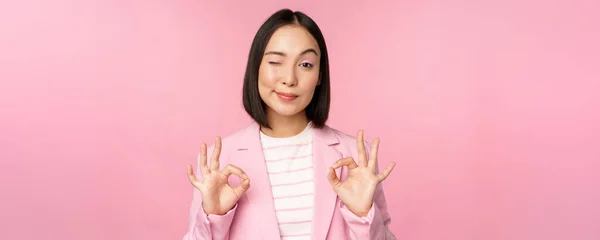 De acuerdo, excelente. Mujer de negocios en traje corporativo, mostrando ok, gesto de aprobación, recomendando smth, dar retroalimentación positiva y sonriendo complacido, posando sobre fondo rosa — Foto de Stock