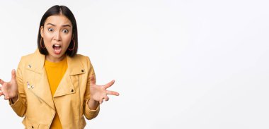 Asyalı kızgın kadın tartışıyor, el sıkışıyor kızgın ve çığlık atıyor, sinirli bir yüzle bağırıyor, beyaz arka planda duruyor.