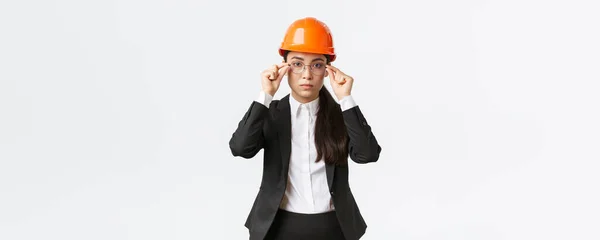 Ας πιάσουμε δουλειά. Σοβαρή εμφάνιση αυτοπεποίθηση γυναίκα επικεφαλής μηχανικός της Ασίας επιθεωρήσει την επιχείρηση, φορώντας κράνος και κοστούμι ασφαλείας, βάλτε τα γυαλιά, στέκεται λευκό φόντο, έτοιμος να εργαστεί — Φωτογραφία Αρχείου