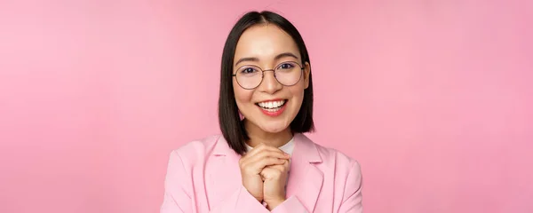 Närbild porträtt av leende glad affärskvinna i glasögon, knyta händerna tillsammans tacksam, upphetsad av smet, tiggeri eller säga snälla, står över rosa bakgrund — Stockfoto