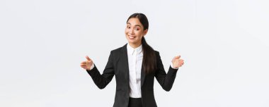 Gülümseyen Asyalı satış elemanı müşteriye ürün satıyor, büyük nesneleri şekillendiriyor ve kameraya dostça sırıtıyor. İş kadını projesini halka tanıtıyor, geniş bir daire ve beyaz arka plan tanıtıyor.