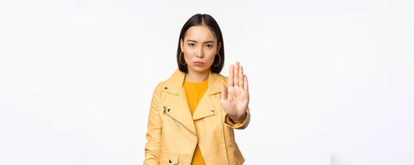 Ernstes und besorgtes asiatisches Mädchen ausstreckt Handfläche, Stoppgeste, verbietet etliches, verbietet, steht über weißem Studiohintergrund — Stockfoto
