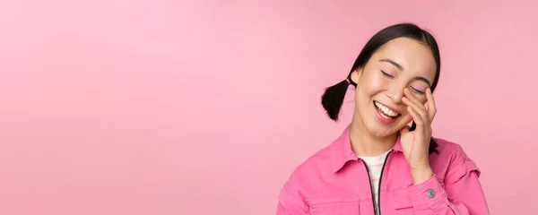Primer plano retrato de hermosa chica asiática mirando entusiasta y sonriente, riendo y sonriendo, de pie feliz sobre fondo rosa —  Fotos de Stock