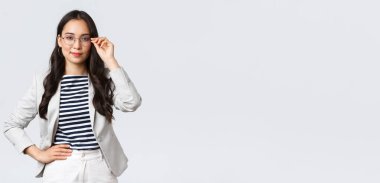 İş, finans ve istihdam, başarılı kadın girişimciler konsepti. Gözlüklü ve beyaz takım elbiseli kendine güvenen iş kadını buluşmaya hazır gülümsüyor, mutlu, kararlı.