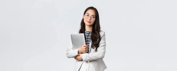 Negocios, finanzas y empleo, concepto de emprendedoras exitosas. Joven mujer de negocios asiática, empleado de banco en gafas celebración de la computadora portátil y mirando a la cámara — Foto de Stock