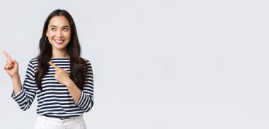 Yaşam tarzı, insanların duygu konsepti. Heyecanlı, yakışıklı, gülümseyen Asyalı kız mükemmel bir ürün bulduğuna sevindi, reklamları işaret etti ve memnun göründü, tanıtımı tavsiye etti.