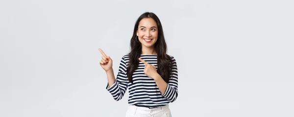 라이프 스타일, 사람들의 감정 개념. 화려 한 미소를 짓고 있는 멋지게 생긴 이시아 소녀는 광고에 손가락을 남겨 놓고 만족 해 하는 모습을 보이며 즐겁게 웃고 있다. — 스톡 사진