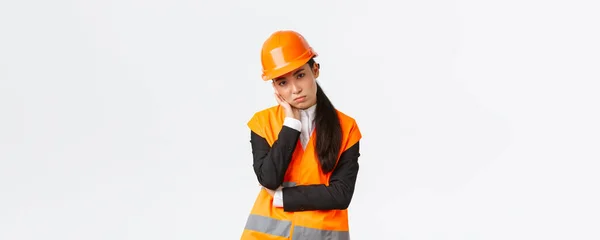 Gloomy e incomodado asiático engenheiro feminino cansado de trabalho, desgaste capacete de segurança e casaco reflexivo, magra na palma da mão e olhando irritado para gerente de construção, ouvindo discurso chato — Fotografia de Stock