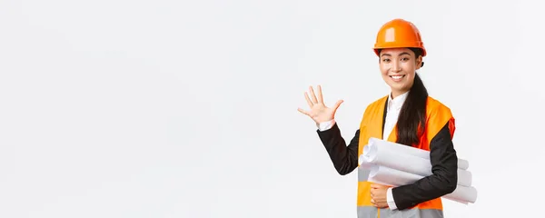 Glimlachende professionele Aziatische vrouwelijke ingenieur, architect geven vijf maanden voor de bouw, dragen blauwdruk van het project en kijken naar de camera, garanderen afwerking werk in de tijd, witte achtergrond — Stockfoto