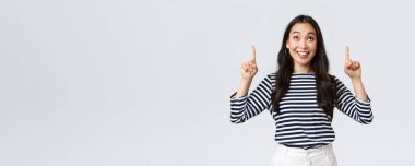 Yaşam tarzı, insanların duygu konsepti. Heyecanlı, yakışıklı, gülümseyen Asyalı kız mükemmel bir ürün bulduğundan memnun olmuş, reklamları işaret ediyor ve memnun görünüyor, tanıtım öneriyor.