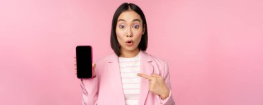 Şaşırmış, hevesli Asyalı iş kadını cep telefonu ekranı, akıllı telefon uygulaması arayüzü, pembe arka planda duran