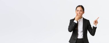 Yorgun kadın ofis müdürü, takım elbiseli girişimci sağ elini uzatıp esniyor. Sıkıcı ya da bitkin Asyalı iş kadını geç saatlere kadar çalışıyor, projeyi gösteriyor, beyaz arka planda duruyor