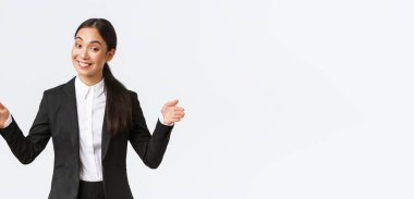 Gülümseyen Asyalı satış elemanı müşteriye ürün satıyor, büyük nesneleri şekillendiriyor ve kameraya dostça sırıtıyor. İş kadını projesini halka tanıtıyor, geniş bir daire ve beyaz arka plan tanıtıyor.