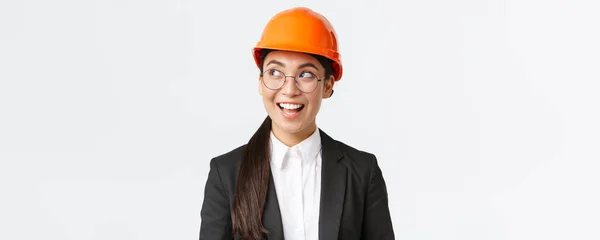 富有创造力的亚洲女建筑师的特写镜头闪烁着迷人的意念，身穿西装、头戴安全帽的建筑工程师笑容满面，站在白色的背景上 — 图库照片