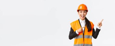 İnşaat, inşaat ve endüstriyel konsept. Heyecanlı, gülümseyen Asyalı kadın emlakçı ev müşterileri satıyor, mühendis proje gösteriyor, mimar sağ üst köşeyi işaret ediyor.