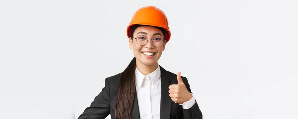 Close-up van professionele tevreden aziatische vrouwelijke chief engineer, architect in business suit en veiligheidshelm tonen duimen-up in goedkeuring, geven toestemming, aanbevelen bouwbedrijf — Stockfoto