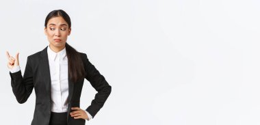 Şüpheci ve garip Asyalı genç iş kadını, siyah takım elbiseli satış elemanı küçük bir şeyi şekillendiriyor ve boyut olarak hayal kırıklığına uğramış görünüyor, ufak tefek şeylerle eğlenmiyor, beyaz arka plan.