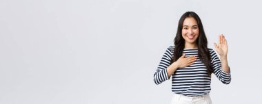 Yaşam tarzı, insanların duyguları ve gelişigüzel kavramlar. Dürüst ve samimi Koreli kız söz veriyor, kollarını kaldırıp kalbe uzanıyor, gülümsüyor ve yemin ediyor, yemin ediyor.