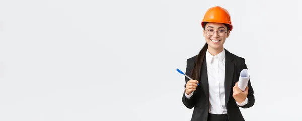微笑成功的女企业家，戴头盔和西服的首席建筑工程师，手持蓝图和钢笔，与建筑供应商签署合同，白人背景 — 图库照片