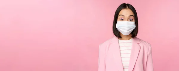 Portrait de femme d'affaires asiatique en masque facial médical, costume, concept de travail de bureau pendant la pandémie covid-19, debout sur fond rose — Photo