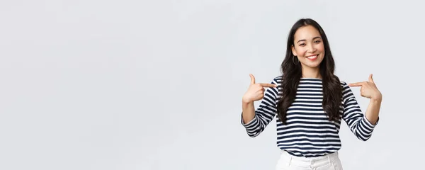 Estilo de vida, belleza y moda, concepto de emociones de la gente. Sonriente mujer de aspecto amigable dispuesta a ayudar, señalándose con mirada agradable, presumiendo de sus propios logros, fondo whtie — Foto de Stock