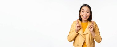 Heyecanlı Asyalı kadın portresi umut dolu, dua eden, yalvaran, haber bekleyen, beyaz arka planda duran, mutlu gülümseyen,